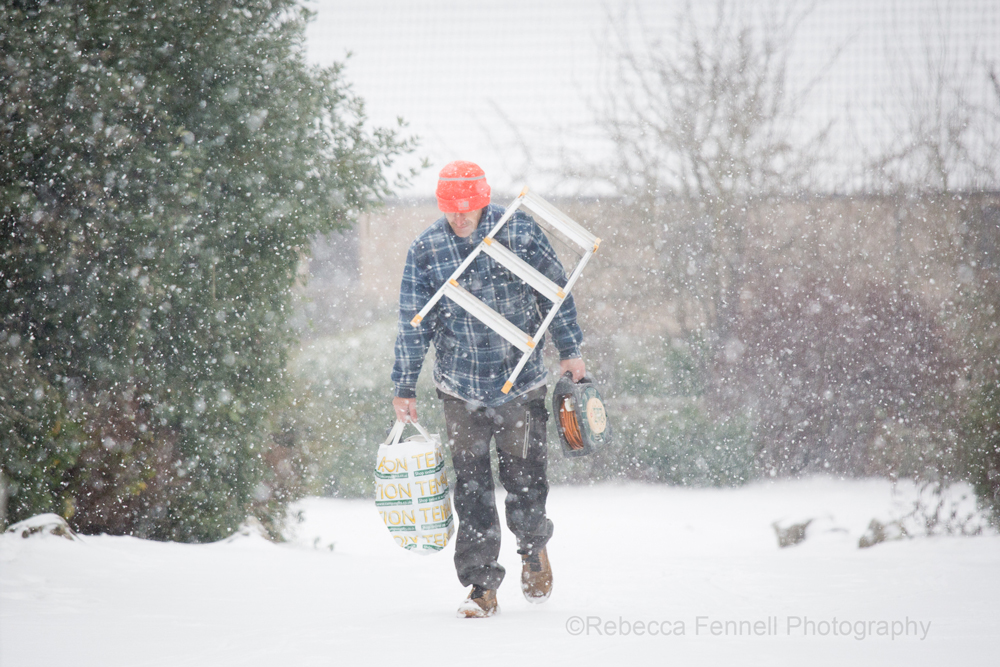 Man walking in snow with lots of bags and ldder